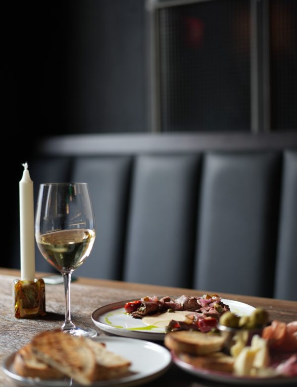 Sophisticated dining setup with wine, appetizers, and candle on a cozy table setting.